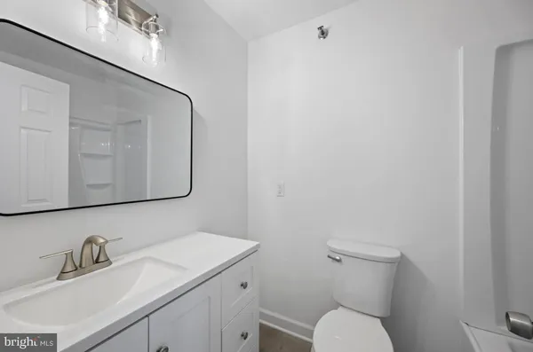 a bathroom with a toilet sink vanity and mirror