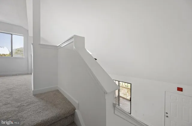 a view of stairs and an empty room with windows
