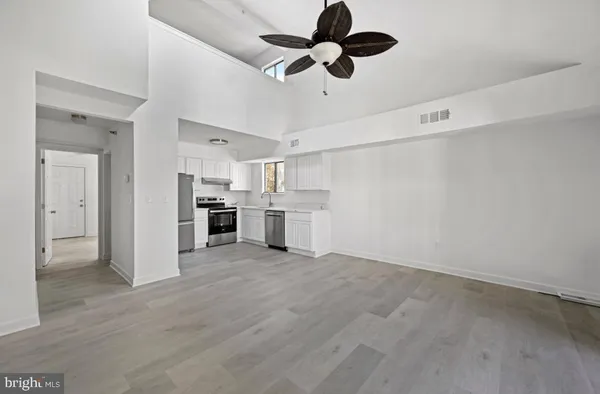 an empty room with wooden floor ceiling fan and windows