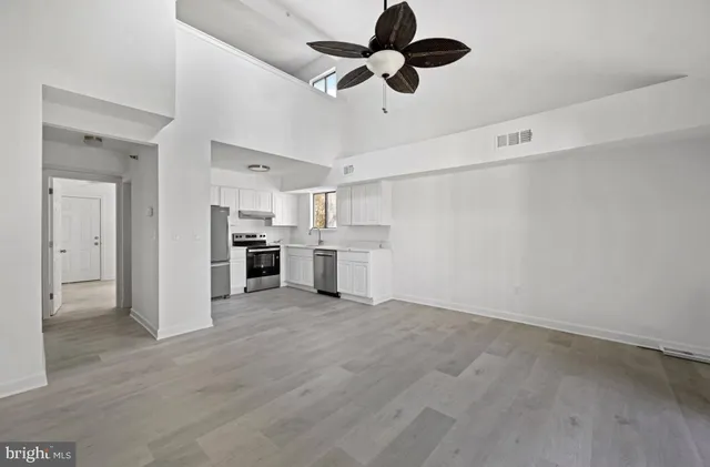 an empty room with wooden floor ceiling fan and windows