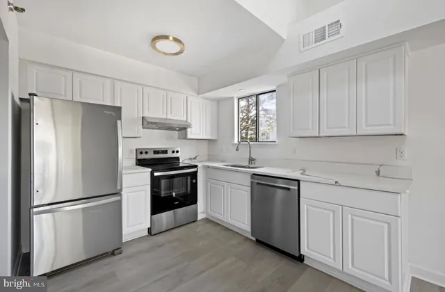 a kitchen with white cabinets and stainless steel appliances