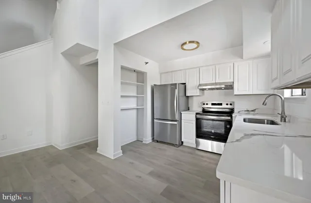 a kitchen with granite countertop a refrigerator and a stove top oven