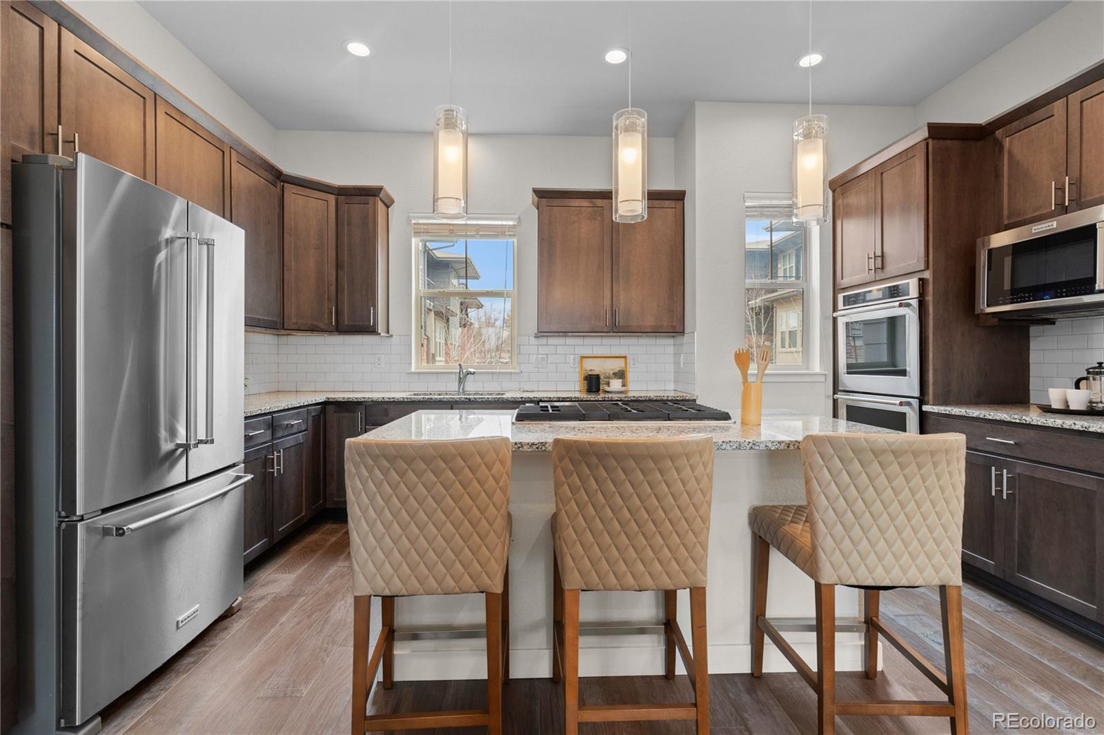 188 South Locust Street Denver, CO 80224 - Photo 5 of 29 a kitchen with stainless steel appliances granite countertop a refrigerator a stove a kitchen island and chairs with wooden floor