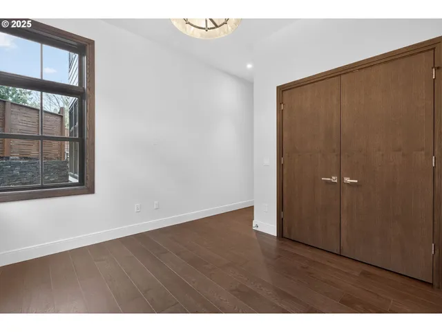 a view of an empty room with wooden floor and windows