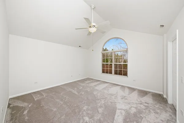 an empty room with windows and ceiling fan