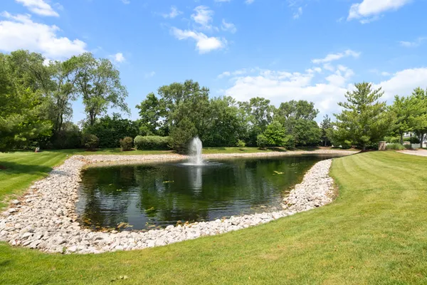 a view of a lake with a yard and large trees