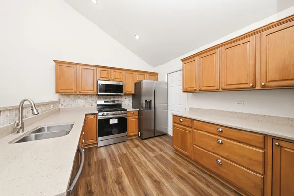 a kitchen with granite countertop a refrigerator stove top oven and sink