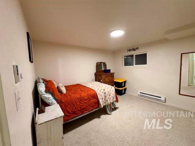 3197 Neeley Road American Falls, ID 83211 - Photo 32 of 45 Light-toned walls and carpet flooring define this room, featuring an egress window, built-in baseboard heating, and an overhead light fixture