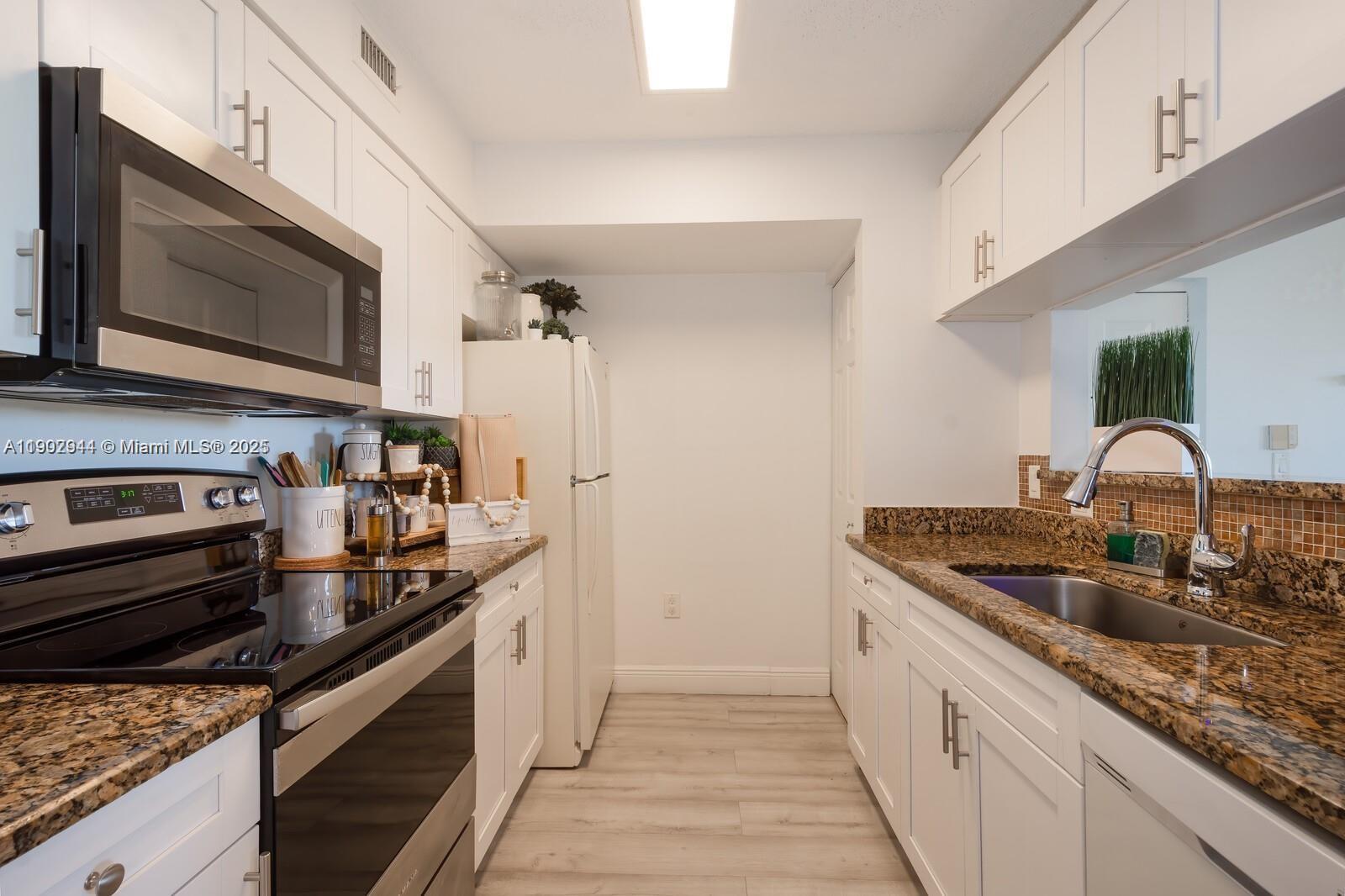 12160 St Andrews Place, Unit 108 Miramar, FL 33025 - Photo 2 of 16 a kitchen with stainless steel appliances granite countertop a sink and a stove