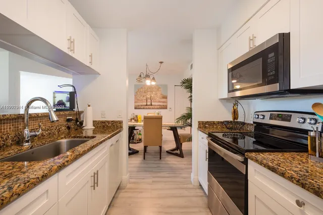 a kitchen with granite countertop a sink stove and cabinets