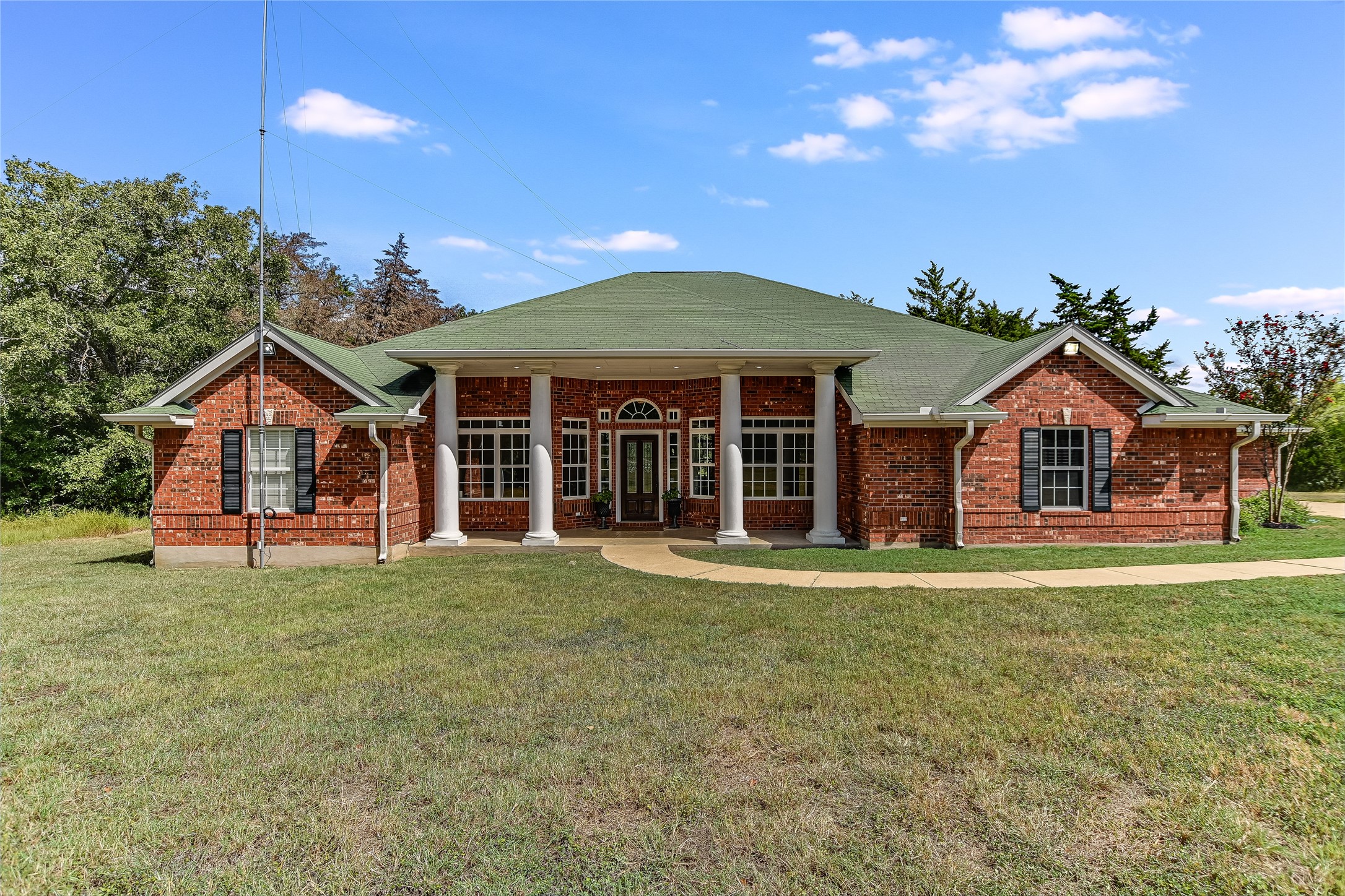 A classic brick exterior with a welcoming columned entry and green roof offers timeless curb appeal.
