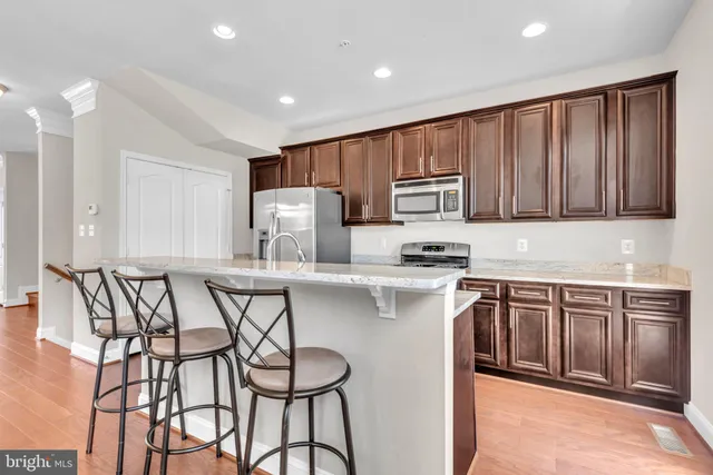 a kitchen with stainless steel appliances granite countertop a stove a sink dishwasher and a refrigerator with wooden cabinets