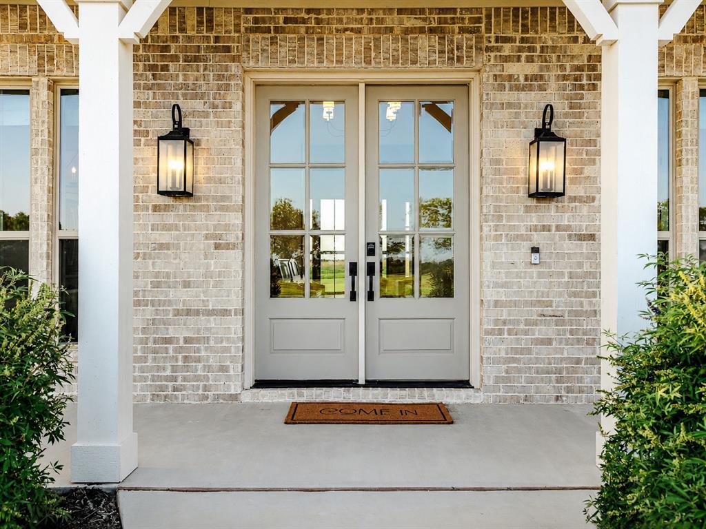 11032 Gregory Road Sanger, TX 76266 - Photo 6 of 40 Welcoming entry featuring dual French doors with multiple glass panes, flanked by symmetrical black lantern sconces and white structural columns