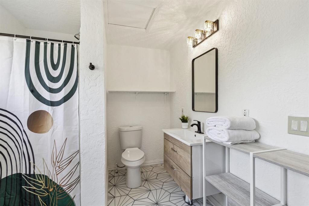 2435 West 10th Street Dallas, TX 75211 - Photo 30 of 38 a bathroom with a sink mirror vanity and toilet