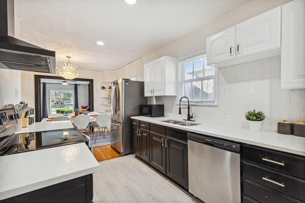 2435 West 10th Street Dallas, TX 75211 - Photo 9 of 38 a kitchen with stainless steel appliances a sink dishwasher a refrigerator a stove and white cabinets with wooden floor