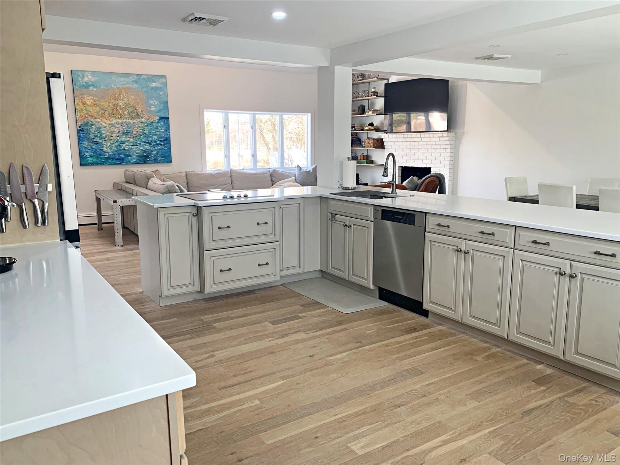 56861 Private Rd B (main) Southold, NY 11971 - Photo 34 of 34 Kitchen with open floor plan, a peninsula, light wood-style floors, stainless steel dishwasher, and light stone countertops