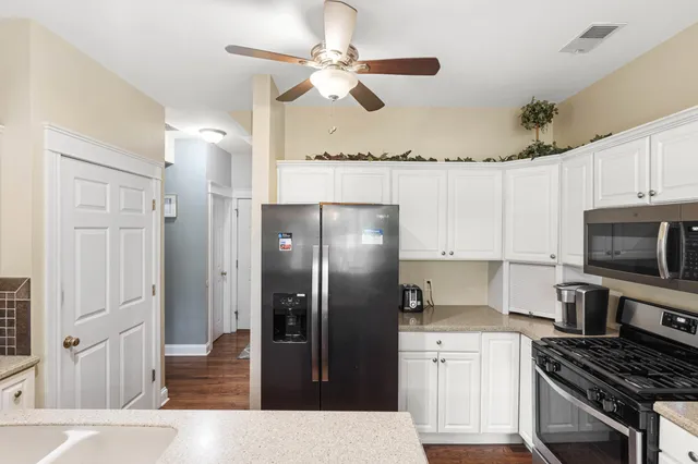 a kitchen with stainless steel appliances a refrigerator a sink and white cabinets