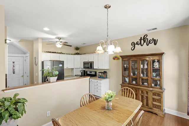 a view of a dining room and livingroom with furniture wooden floor a chandelier