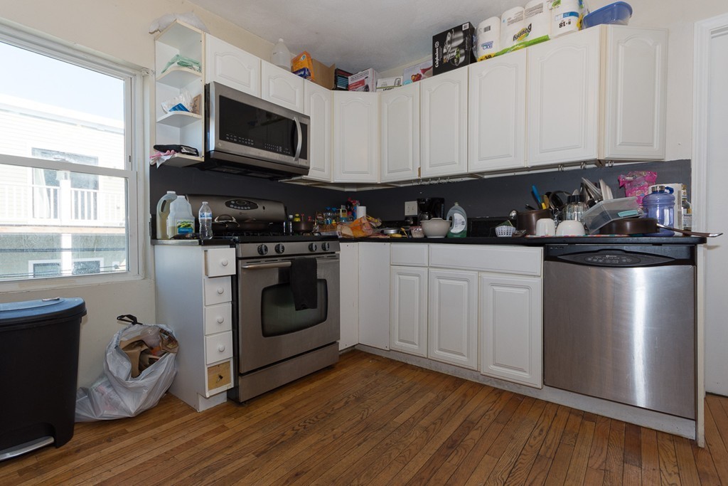 5 Everett Court Boston, MA 02128 - Photo 2 of 9 a kitchen with granite countertop a stove top oven a sink dishwasher and white cabinets with wooden floor