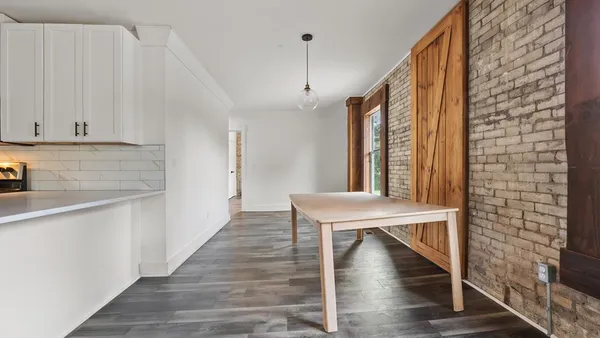 a dining room with wooden floor table and chairs