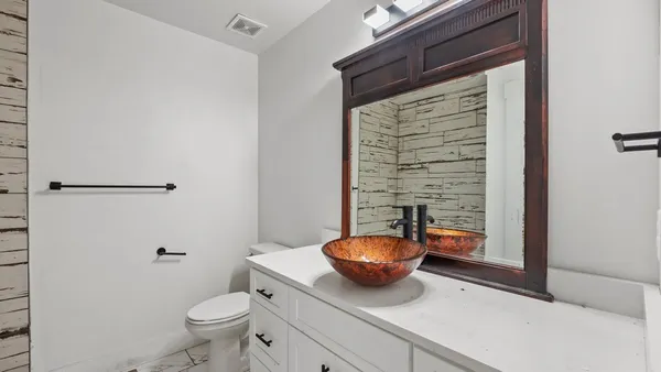 a bathroom with a granite countertop toilet and a sink