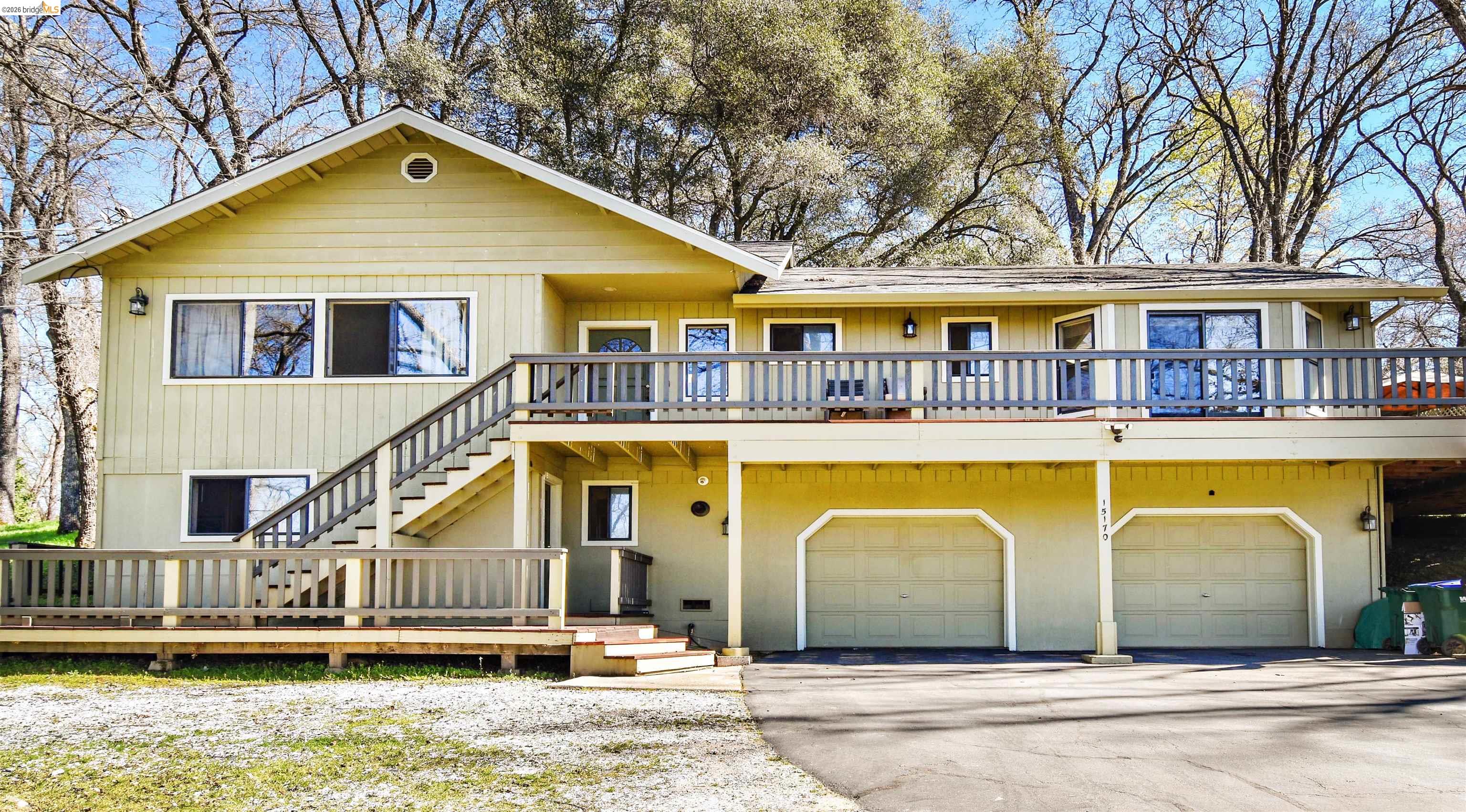 View of front of property with a deck, driveway, and an attached garage