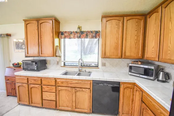 a kitchen with stainless steel appliances granite countertop a sink a window and cabinets