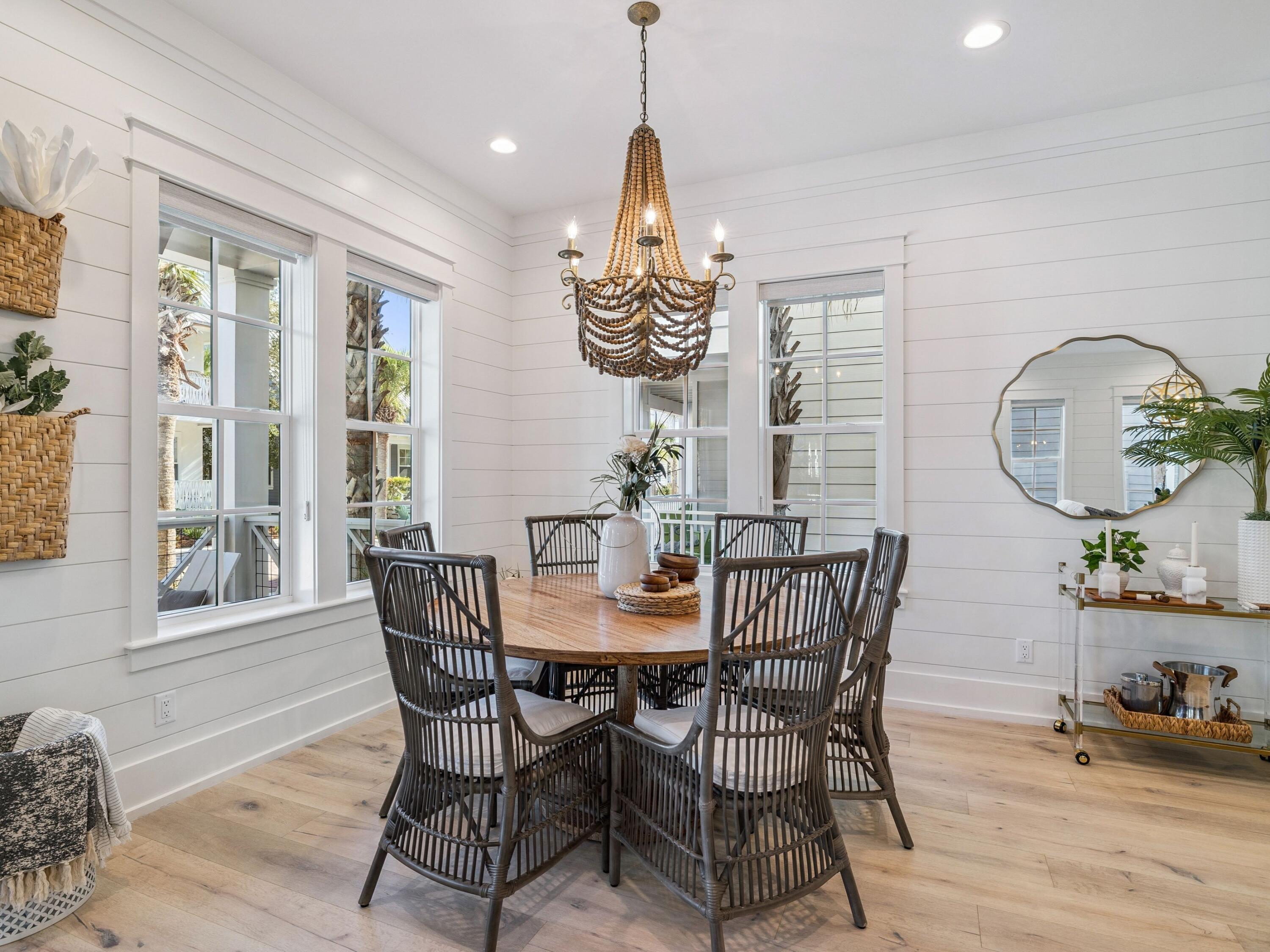 205 Seacrest Beach Boulevard Seacrest, FL 32461 - Photo 15 of 39 a dining room with wooden floor a chandelier a glass table and chairs