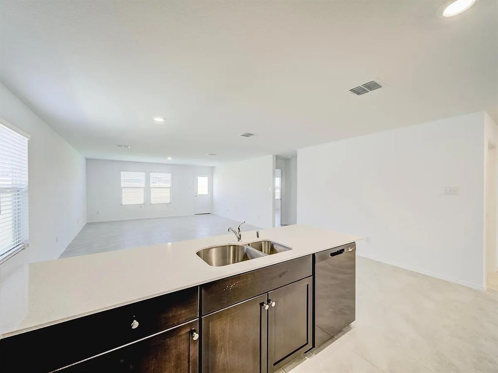 352 Sun Bluff Road Fort Worth, TX 76052 - Photo 7 of 33 Kitchen island featuring a dual basin sink, white countertop, and dark wood cabinetry