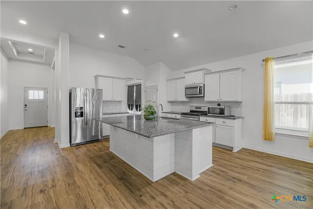 a kitchen with stainless steel appliances granite countertop a refrigerator and a stove top oven