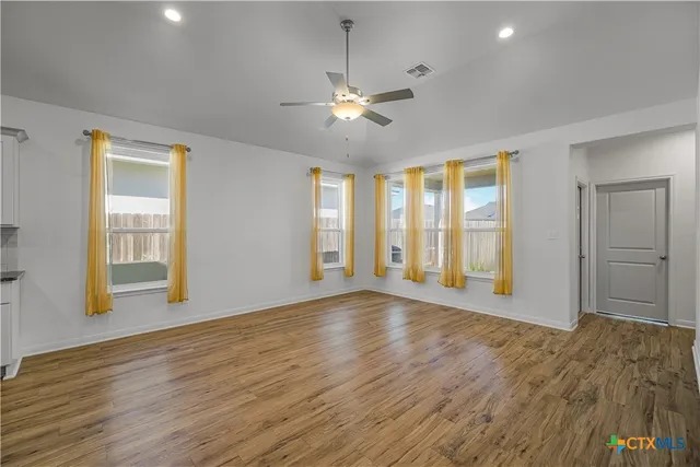 a view of an empty room with window and wooden floor