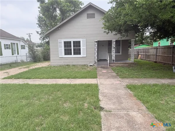a front view of a house with a yard and trees