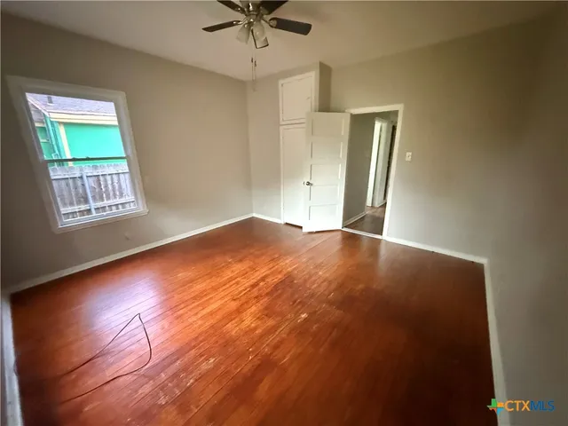an empty room with window and ceiling fan