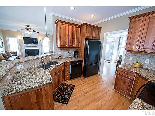 208 Okamato Street Raleigh, NC 27603 - Photo 9 of 25 Open kitchen with cherry cabinets, granite countertops, tile backsplash, smoothtop range, serving bar, recessed lighting and hardwoods.