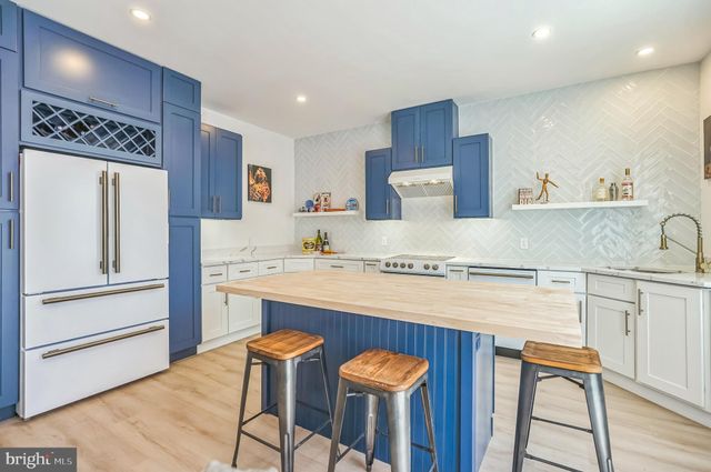 a kitchen with stainless steel appliances granite countertop a table chairs sink and cabinets