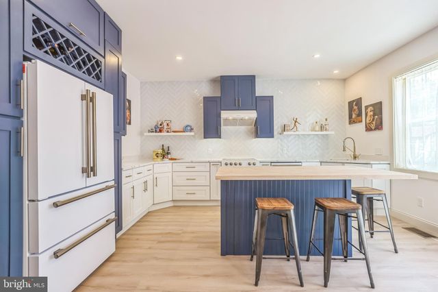 a kitchen with granite countertop a refrigerator a stove a sink and white cabinets with wooden floor