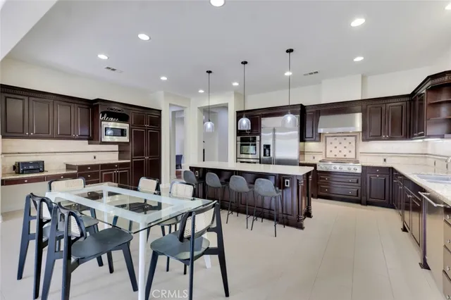 a kitchen with stainless steel appliances kitchen island granite countertop a wooden cabinets and a refrigerator