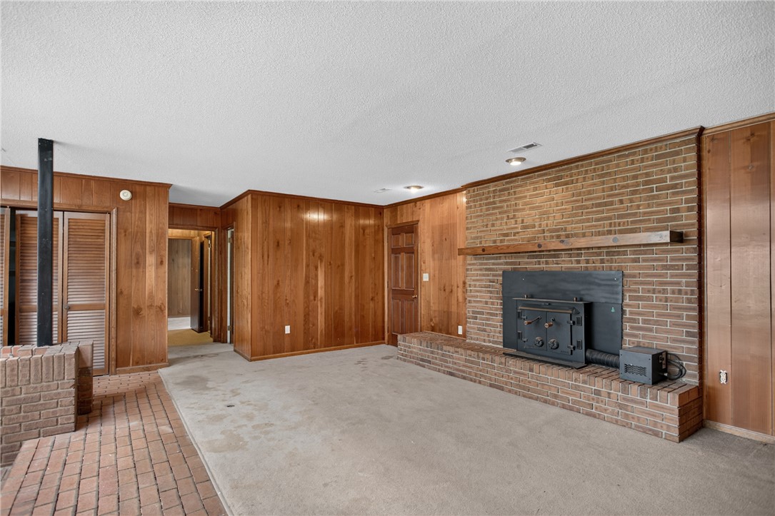 1412 Simpson Road Pendleton, SC 29670 - Photo 12 of 48 A spacious living area featuring warm wood paneling and a substantial brick fireplace hearth.