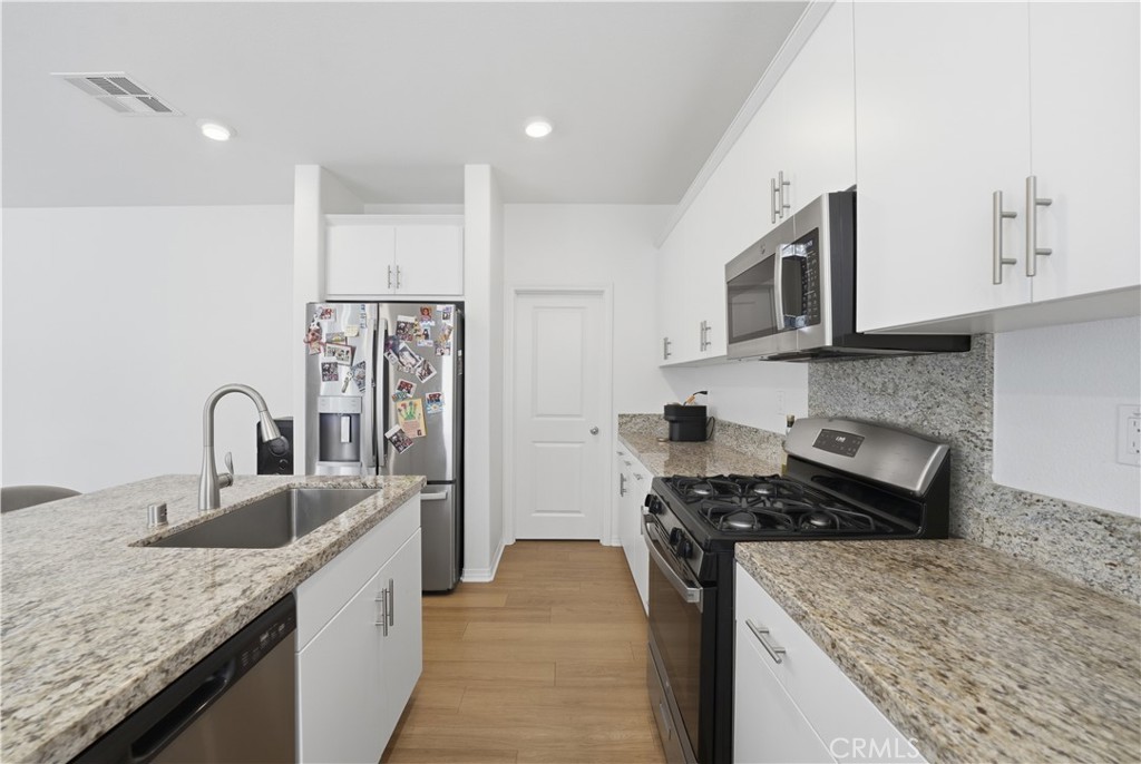 2522 Gunner Ridge Way Rialto, CA 92377 - Photo 12 of 28 a kitchen with stainless steel appliances granite countertop a sink stove and refrigerator