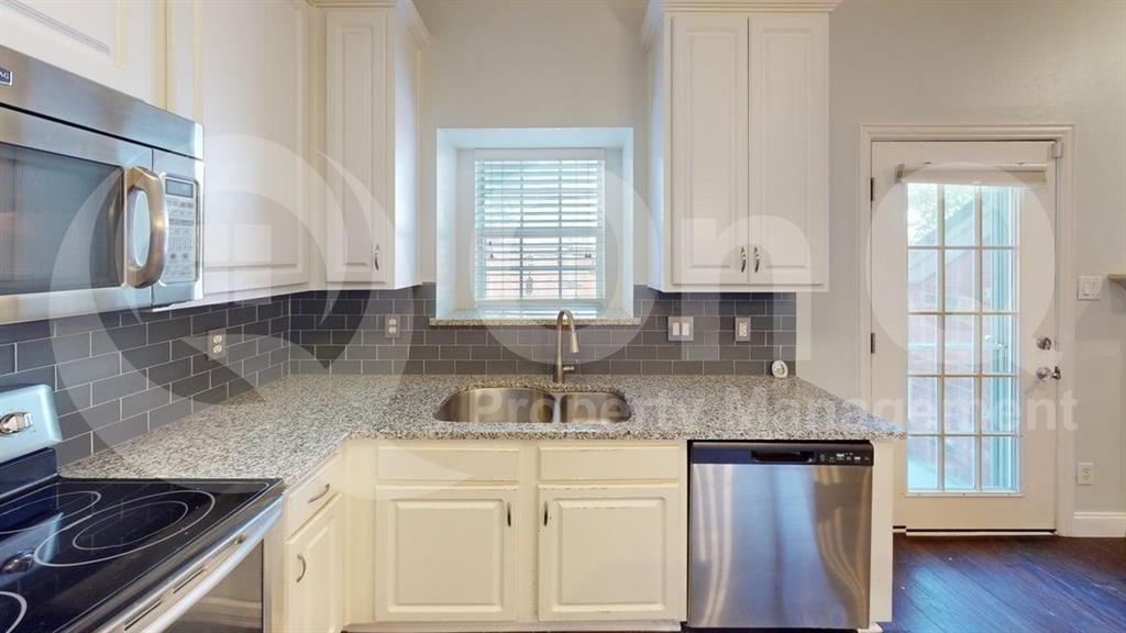 18240 Midway Road, Unit 1204 Dallas, TX 75287 - Photo 2 of 27 Kitchen featuring white cabinetry, stainless steel appliances, granite-style countertops, gray subway tile backsplash, and dark wood-finish flooring