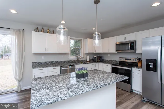 a kitchen with a center island a counter space stainless steel appliances and cabinets