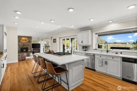 a kitchen with stainless steel appliances granite countertop a table chairs sink and cabinets