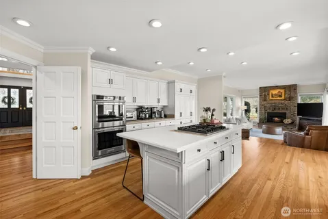 a kitchen with stainless steel appliances a sink a stove a refrigerator and chairs