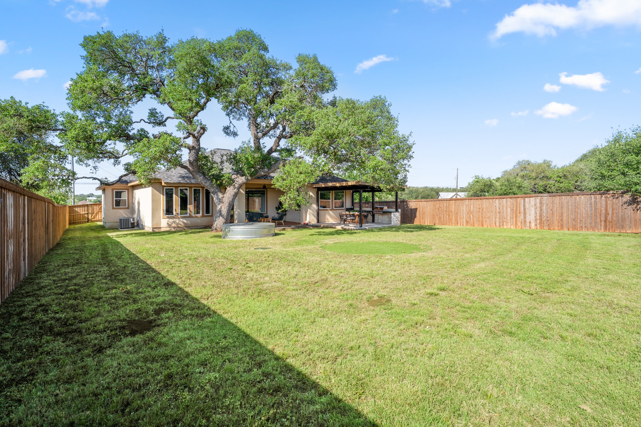 128 Hiram Cook Blanco, TX 78606 - Photo 27 of 40 Expansive backyard featuring a mature tree, large grassy area, and wood privacy fencing