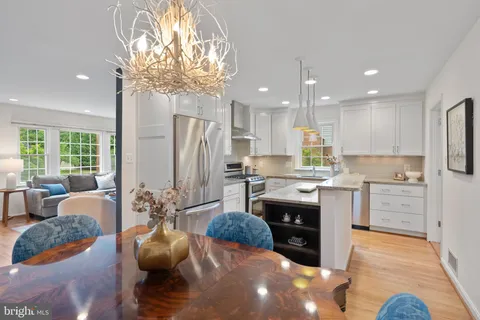 a kitchen with stainless steel appliances granite countertop a refrigerator a sink dishwasher a stove and white cabinets with wooden floor