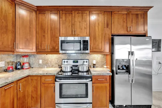 a kitchen with stainless steel appliances granite countertop a refrigerator a stove a sink and dishwasher