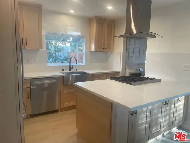 a kitchen with a sink dishwasher a stove and a refrigerator with wooden cabinets