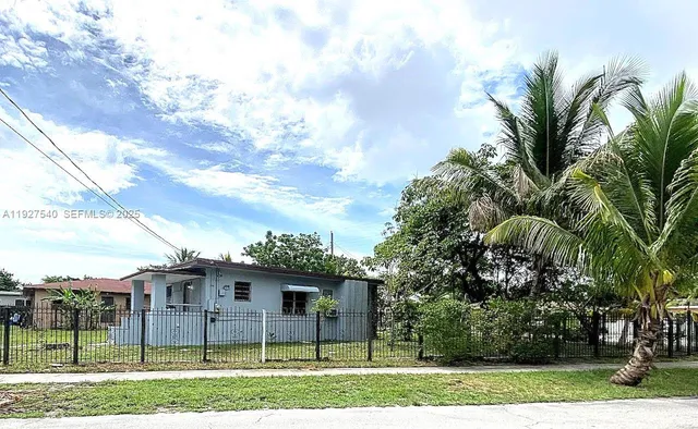 a view of a white house with a big yard and potted plants