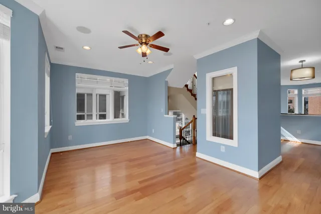 a view of empty room with wooden floor and fan
