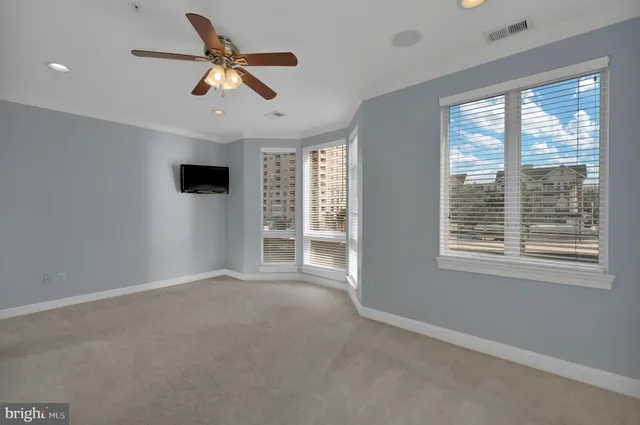 an empty room with ceiling fan and windows